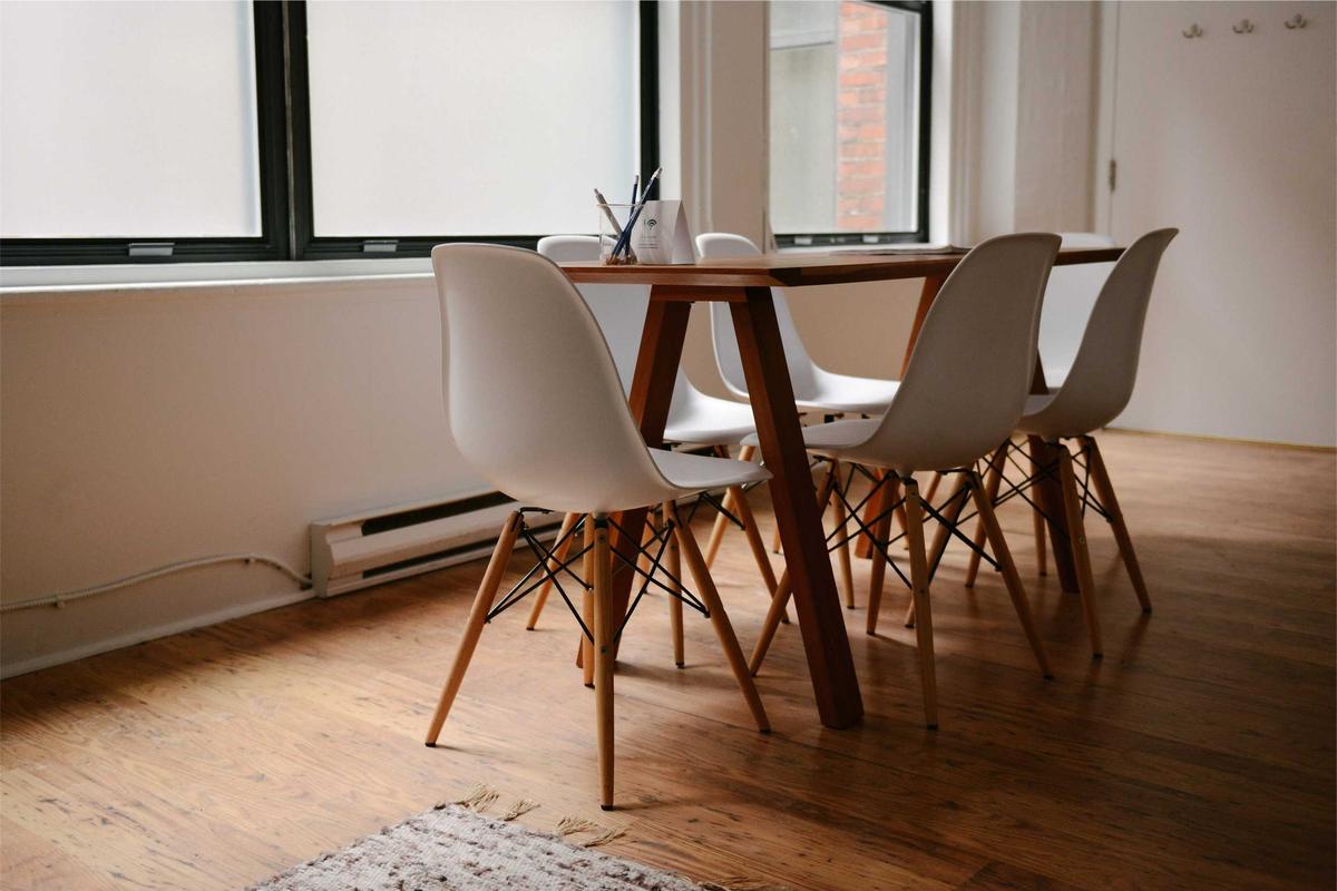 Une grande table en bois près des fenêtres, prête à recevoir.